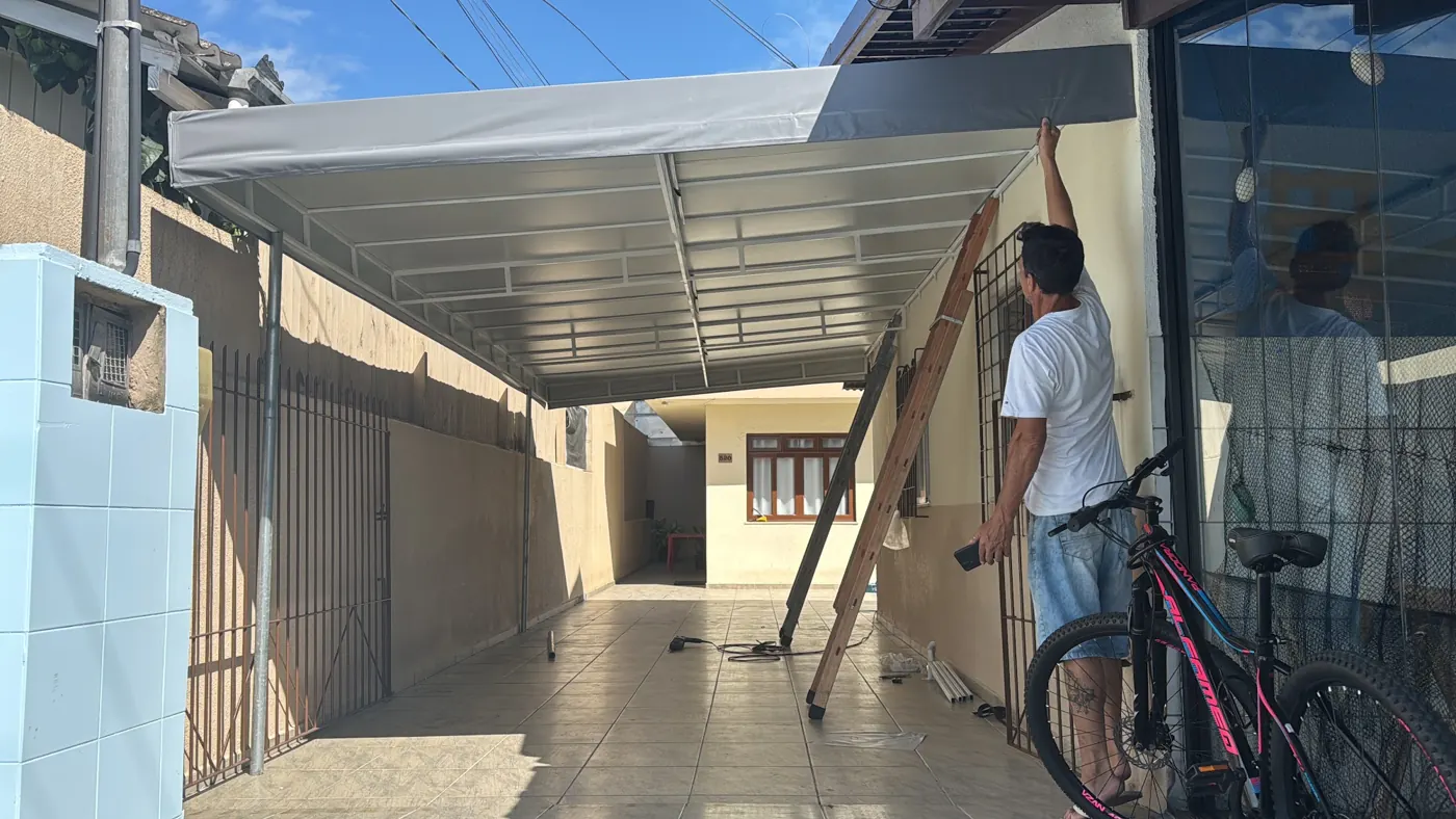 Cobertura de garagem com a equipe na instalação, obra da Tecno Toldos e Lonas