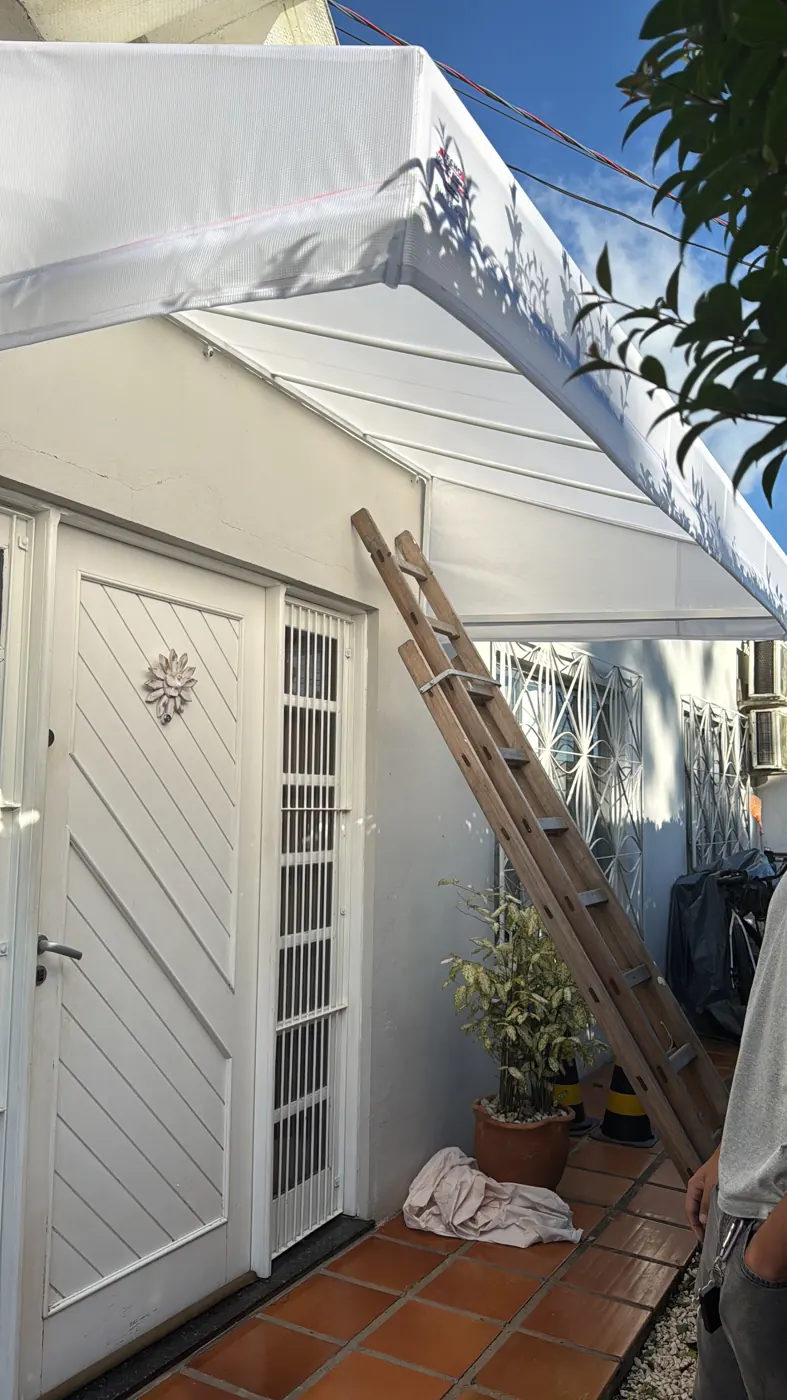 Toldo branco sobre a porta de entrada, obra da Tecno Toldos e Lonas