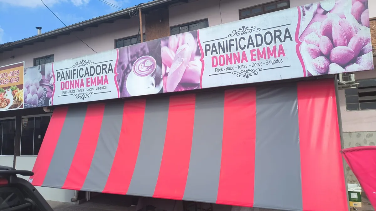 Toldo listrado vermelho e cinza na fachada de uma panificadora
